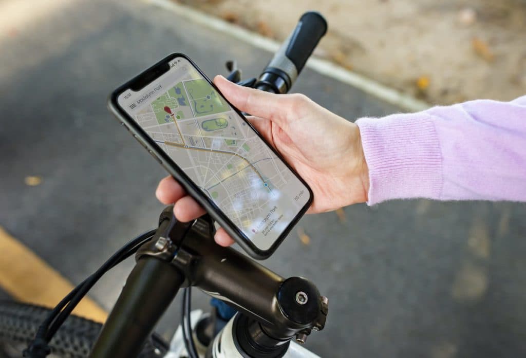 A person on a bike holds a phone featuring a picture of a map.