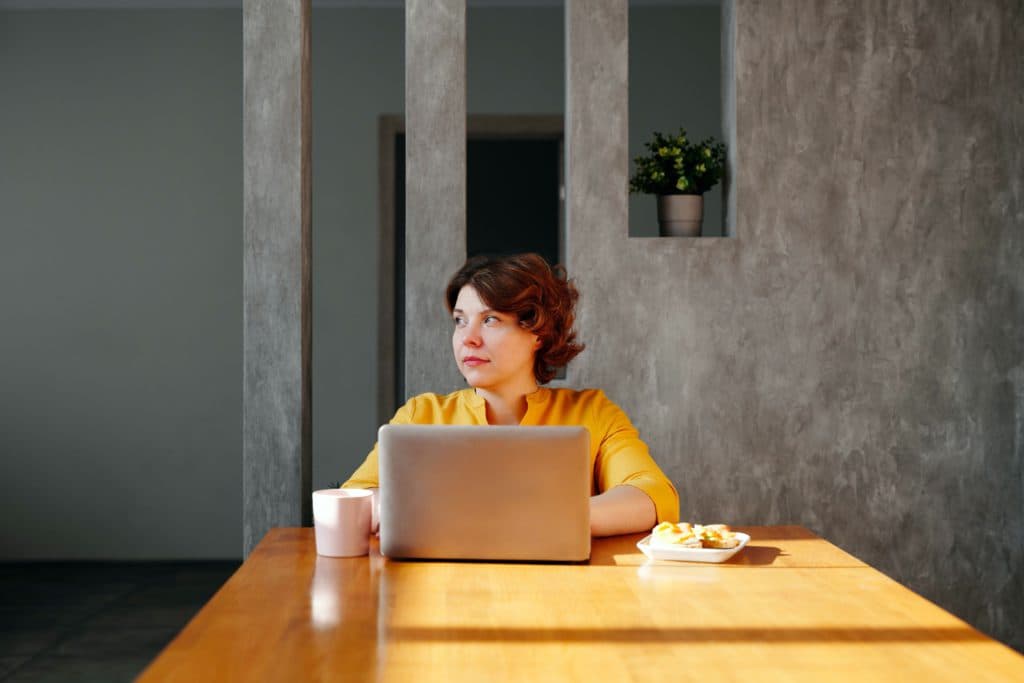 A woman waits at her computer for her remote team's brainstorming session to begin.