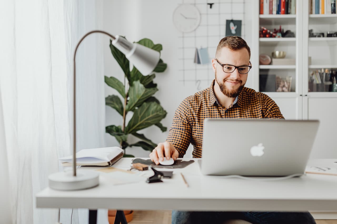 A man works on his laptop while following his company's onboarding plan for adopting new technology.