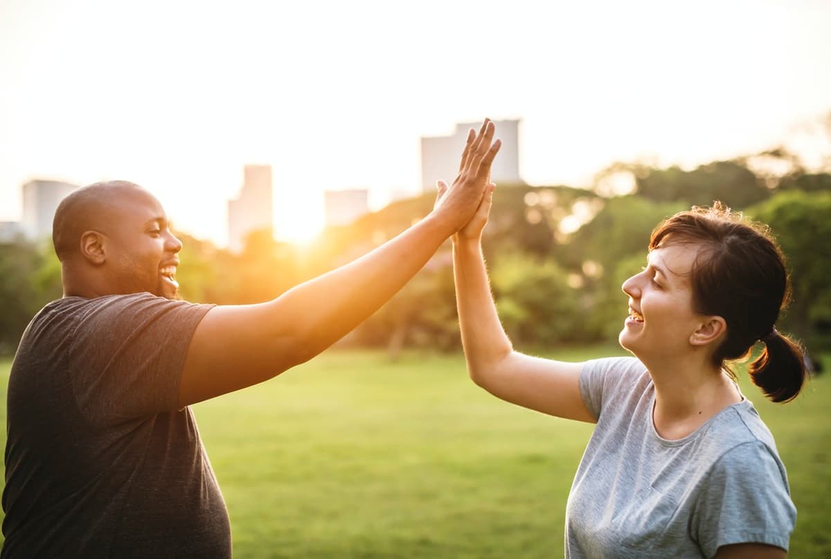 Two co-workers high-five during a hybrid team outing with their remote-first company.