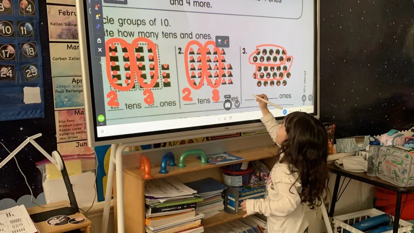 Child writing on a Vibe Board during a classroom activity.