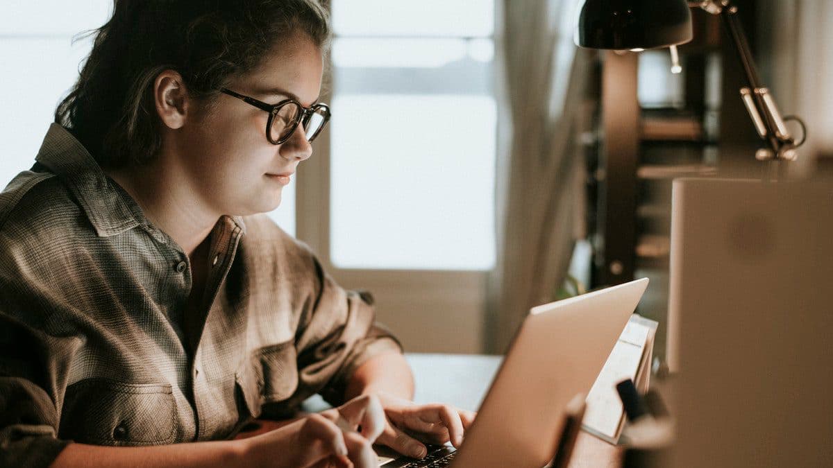 A girl completes schoolwork on her laptop at her own pace, one of the benefits of distance learning.