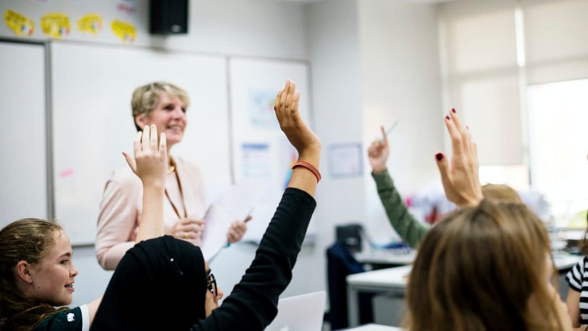 Students raise their hands to answer a question in class.