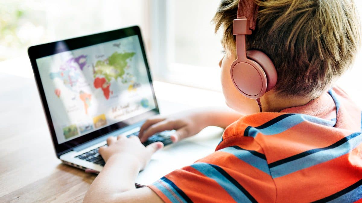 A student learns during an online geography lesson while wearing headphones, following distance learning best practices.