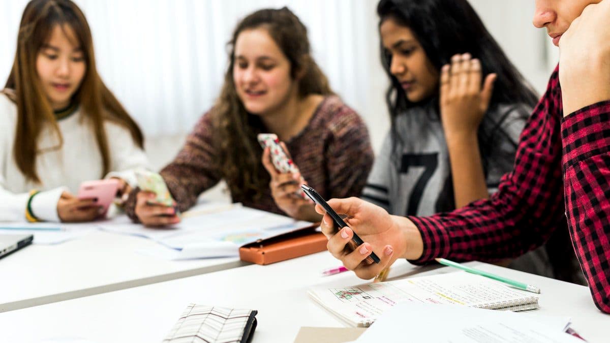 Students using smartphones in class to record and complete assignments.